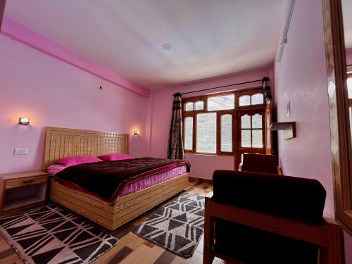 1 dormitorio con paredes rosas, 1 cama y 1 silla en Rajgundha, en Kyelang