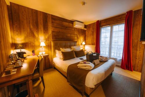 a hotel room with two beds and a desk and a desk at Les Violettes Hotel & Spa in Jungholtz