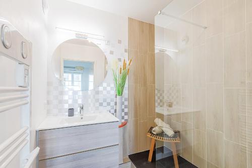 une salle de bain blanche avec un lavabo et un miroir dans l'établissement L'Eden - City Center - DISNEY 8 min, PARIS 28 min - GARE 1 min - PARKING - Free WIFI, à Bussy-Saint-Georges