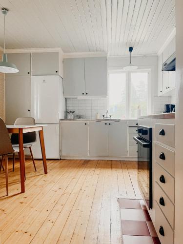 a kitchen with white cabinets and a wooden floor at Charming house with wood stove near lake in Virserum