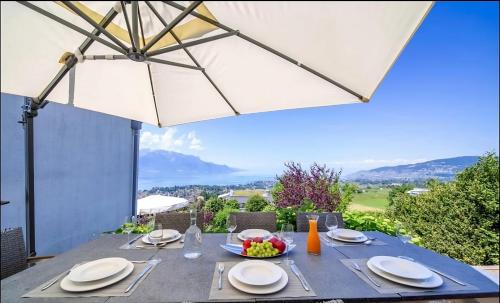 a dining table with an umbrella on a patio at Panoramic Holiday Villa in Montreux in Montreux