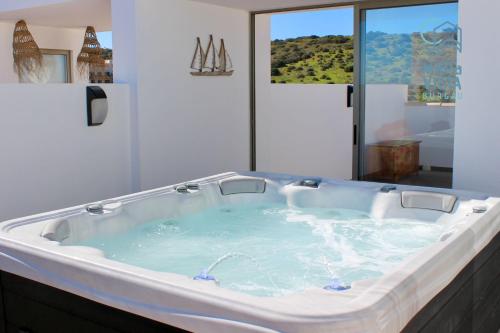 a jacuzzi tub in a bathroom with a window at Mar à Vista Burgau in Burgau