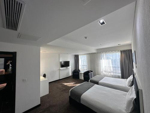 a hotel room with two beds and a television at City Tower Hotel in Ulaanbaatar