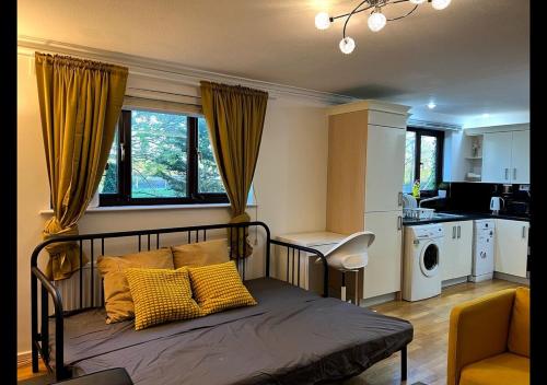 a bedroom with a bed with yellow pillows and a kitchen at London 2 bed-Apartment BEAUTIFUL in Borehamwood