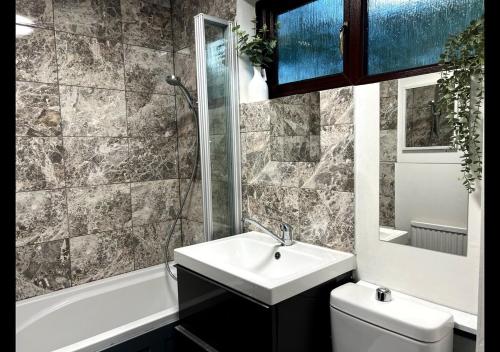 a bathroom with a sink and a toilet and a tub at London 2 bed-Apartment BEAUTIFUL in Borehamwood