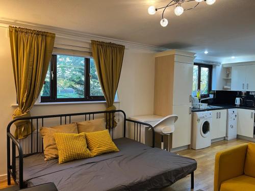 a bedroom with a bed with yellow pillows and a kitchen at London 2 bed-Apartment BEAUTIFUL in Borehamwood