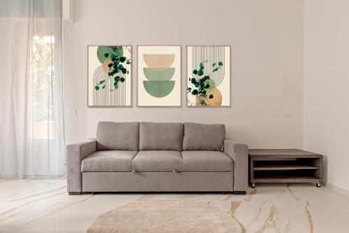 a living room with a couch and three paintings at SEASIDE LOFT - 3 camere,2 bagni a 300 mt dal mare in Marina di Massa