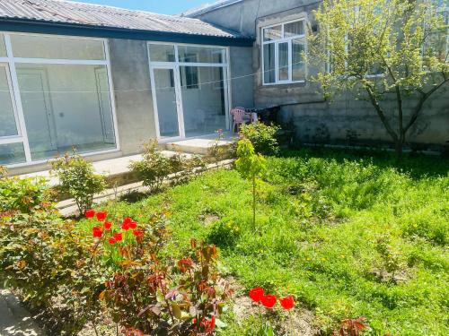 a yard with red flowers in front of a house at House in Quba in Quba