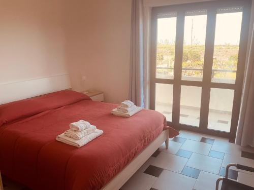 a bedroom with a red bed with towels on it at Casa Vacanza Demetra in Marina di Fuscaldo