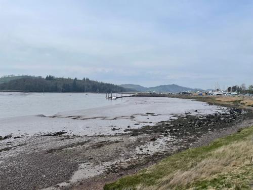 a body of water with a shoreline with trees in the background at Grannys Vintage Coastal Caravan in Kippford