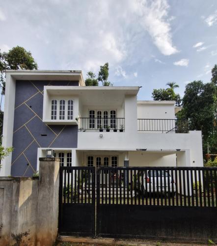 a white house with a black fence at Parthees Homestay in Meppādi