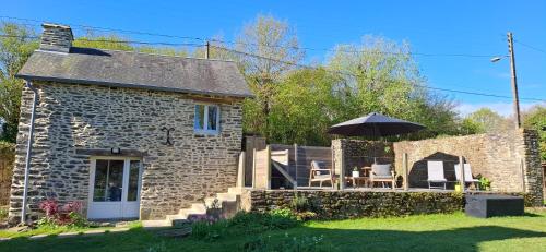 une maison en pierre avec une table et un parasol dans l'établissement Les gîtes de La Petite Taupe - Akotee, à Saint-Omer