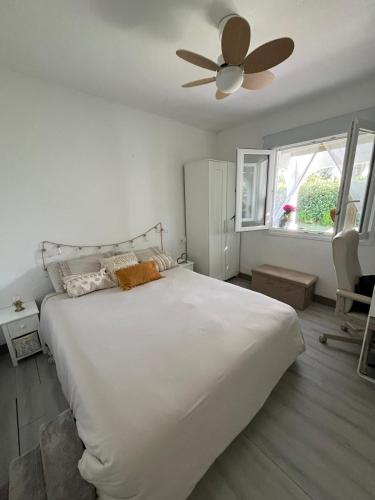 a bedroom with a large white bed with a ceiling fan at Menorca Palm Villa in Cala en Blanes
