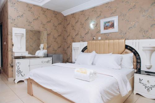a bedroom with a white bed with a wooden headboard at World Class Hotel & Apartments in Abuja