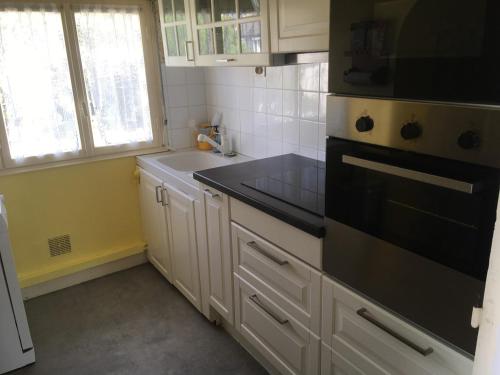 La cuisine est équipée de placards blancs et d'un four avec plaques de cuisson noires. dans l'établissement An Dorzell beach, à Cléder