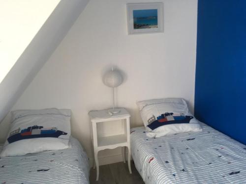 une chambre avec deux lits et une lampe sur une table dans l'établissement An Dorzell beach, à Cléder
