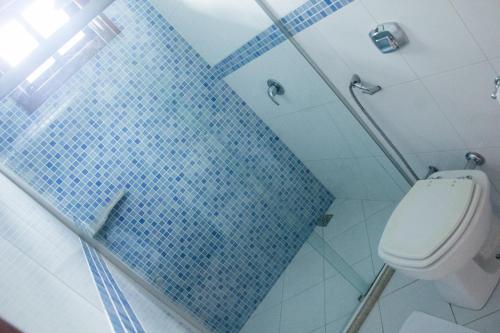 a bathroom with a toilet and a blue tile wall at Pousada da Mata in Iriri