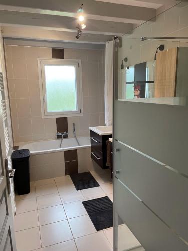 une salle de bain avec une baignoire, un lavabo et une fenêtre dans l'établissement Charmante maison basque entre ville et campagne, à Arcangues