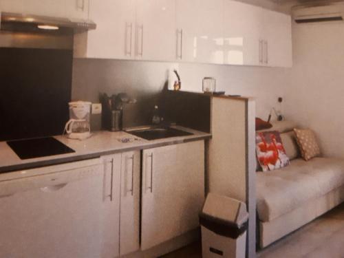 une cuisine avec un évier et un canapé dans une chambre dans l'établissement Magnifique appartement les pieds dans l'eau Presqu'île de Giens, à Hyères