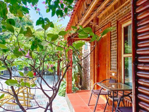 a table and chairs on a porch with a tree at Tam Coc Sunshine Homestay in Ninh Binh