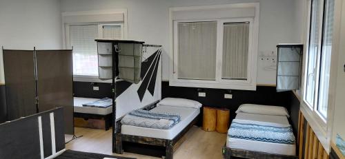 a room with three bunk beds and two windows at Albergue A ROTONDA in Redondela