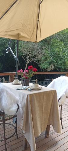 a table under an umbrella on a deck at Vale Infinito Chalé in Córrego do Bom Jesus