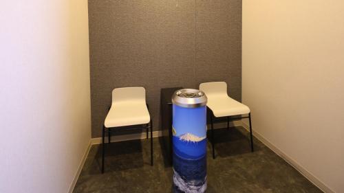two chairs and a water bottle in a room at Dormy Inn Mishima in Mishima