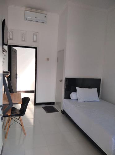 Un dormitorio con una cama y una silla dentro. en Pondok Barokah 1, en Tanjungkarang