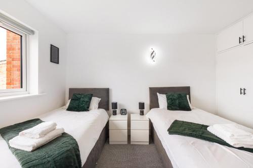 レディングにある1st Floor Flat by Reading Centre Perfect for Contractors and Long-Term Staysの白い壁の客室で、ツインベッド2台が備わります。