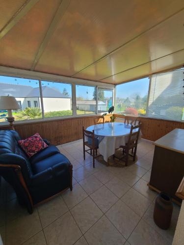 une véranda avec une table et un canapé dans l'établissement Maison de campagne à 12 min de la première plage, à Pluduno