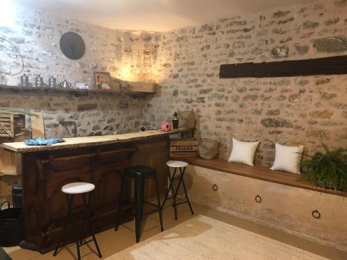 a bar with stools in a room with stone walls at Gite chez mary au domaine du château de ragny in Savigny-en-Terre-Plaine