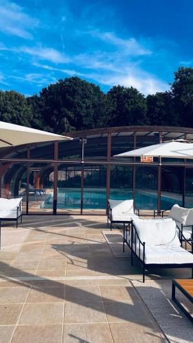 un patio avec des tables et des parasols devant un bâtiment dans l'établissement Gite chez mary au domaine du château de ragny, à Savigny-en-Terre-Plaine
