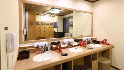 a bathroom with three sinks and a large mirror at Dormy Inn Mishima in Mishima