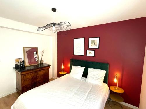 - une chambre dotée d'un mur rouge avec un lit et deux lampes dans l'établissement Charmant T2 au Cœur de Carcassonne- Proche Gare & Centre, à Carcassonne