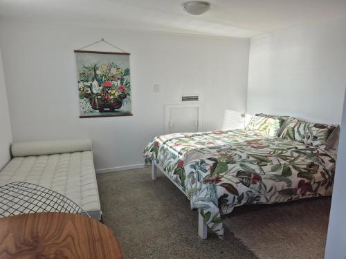 Un dormitorio con una cama y un cuadro en la pared. en Raumati South Beach Studio, en Paraparaumu