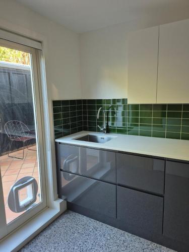 a kitchen with a sink and a sliding glass door at Raumati South Beach Studio in Paraparaumu