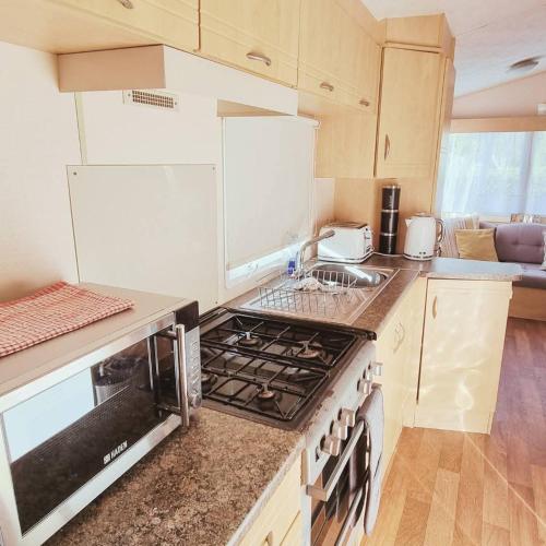 a kitchen with a stove top oven next to a sink at Firs Holiday Home At Southview, Skegness in Winthorpe