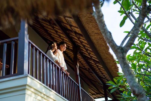 a bride and groom on the balcony of a house at Villa Perle an Idyllic Luxury Retreat in Karangasem