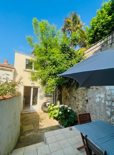 une terrasse avec une table et un parasol bleu dans l'établissement Maison au cœur de Pornic et à 50 m du vieux port, à Pornic