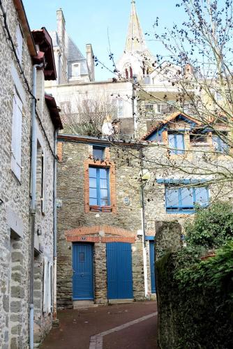 un vieux bâtiment en briques avec des portes bleues dans une rue dans l'établissement Maison au cœur de Pornic et à 50 m du vieux port, à Pornic