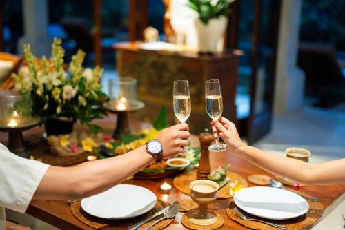 two people holding champagne glasses on a table at Villa Perle an Idyllic Luxury Retreat in Karangasem