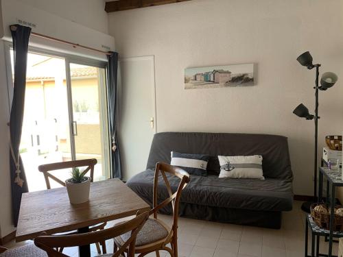 un salon avec un canapé et une table dans l'établissement Appartement tout confort avec terrasse spacieuse, au Grau-dʼAgde