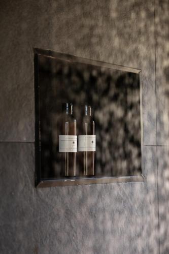 two bottles sitting on a shelf in a mirror at Skaam Cabin Luxe Hideaway with a Naughty Side in Wolseley
