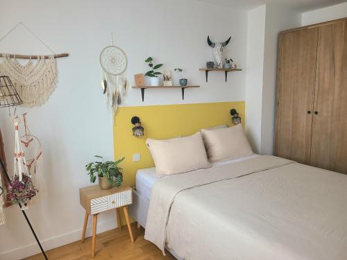 une chambre avec un lit blanc et un mur jaune dans l'établissement Charmant appartement à 2 min du métro, à Pantin