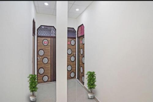 a room with clocks on the wall with two plants at Hotel Joyous inn in Ghaziabad
