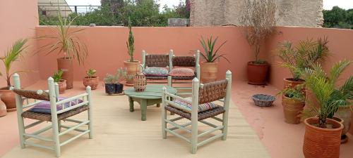 a patio with a table and chairs and potted plants at Maison du soleil in Ghazoua