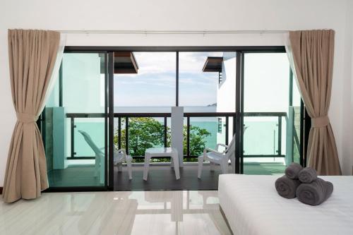 a bedroom with two beds and a large glass window at The Hideout Beachfront in Patong Beach