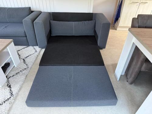 a living room with a blue couch and a rug at Sunny escape hoek van holland in Hoek van Holland