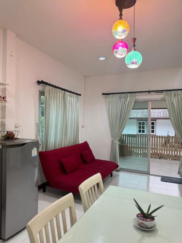 a living room with a red couch and a table at Kids-Dee Home in Sathani Padang Besa