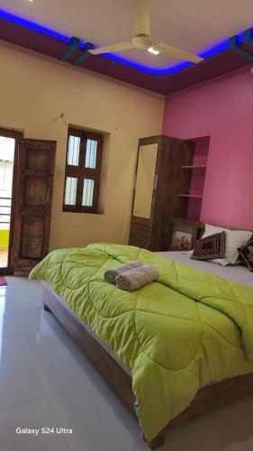 a bedroom with a green bed with a pink wall at Abhi Homestay Hampi in Hampi